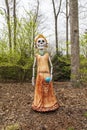a colorful skeleton sculpture of La Catrina one of the most recognizable figures of DÃÂ­a de los Muertos, green trees and plants