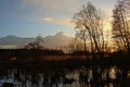 After sunset sky over winter wetland landscape with bare tree silhouettes reflecting in the water