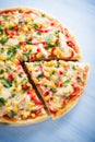 Colorful sliced pizza with mozzarella cheese, chicken, sweet corn, sweet pepper and parsley close up