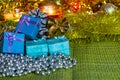 Colorful small gift boxes with gifts among Christmas tinsel and shiny toys and decorations Royalty Free Stock Photo