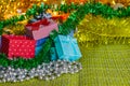 Colorful small gift boxes with gifts among Christmas tinsel and shiny toys and decorations Royalty Free Stock Photo