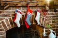 Colorful socks for a gift from Santa Claus hang on the fireplace.