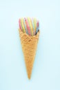 Colorful sour jelly candies in sugar sprinkles in an ice cream cone on a light blue background