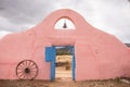 Colorful southwest adobe wall, blue gate, bell, and wagon wheel, New Mexico