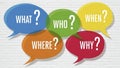 Colorful speech bubbles with question words on a white brick wall questions what Royalty Free Stock Photo