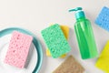 Colorful sponge with dish and green dishwashing soap on light beige background