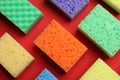 Colorful sponges on red background, flat lay. Cleaning tool Royalty Free Stock Photo