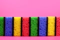 Colorful sponges, Washcloths for cleaning or washing dishes in a row on a pink background
