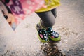 Colorful spotted rain boots baby girl playing with water puddles Royalty Free Stock Photo