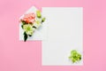 Colorful spring flowers in envelope and white sheet on pink background.