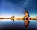 Colorful spring night with traditional Dutch windmills canal in Rotterdam. Wooden pier near the lake shore. Holland