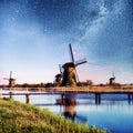 Colorful spring night with traditional Dutch windmills canal in Rotterdam. Wooden pier near the lake shore. Holland