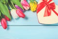 Colorful spring tulip flowers with decorative giftbox on light blue wooden background as greeting card with free space. Mothersday Royalty Free Stock Photo