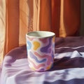 Colorful squiggle mug on satin sheets. blobby design, gen z trend