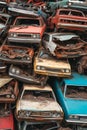 Colorful stack of decaying vintage cars in a scrapyard, reflecting rust and abandonment.