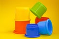 Colorful stacking plastic cups on yellow background. Concept of baby learning toys, colorful pyramid for kids. Royalty Free Stock Photo