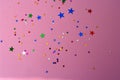 Colorful stars confetti on pink background. Carnival, party decoration.
