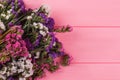 Colorful statice flowers on pink wooden background.