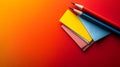 two sharpened colored pencils resting on top of colorful folded paper sheets placed on a vibrant gradient orange to red background Royalty Free Stock Photo