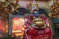 A colorful statue of a man holding a pot gold coins at the Infinite Prosperity: The Year of the Dragon exhibit at the Bellagio