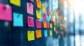 colorful sticky notes arranged on a glass wall in an office setting with blurred background and sunlight coming through windows Royalty Free Stock Photo