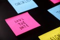 Colorful sticky notes on black board reminder. Save the date written sticker on pineboard. Remember to save the date business