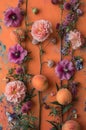 A colorful still life arrangement with flowers and peaches on an orange backdrop