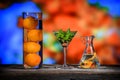 Colorful still life of three glass containers with oranges and some green plant leaves