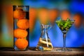 Colorful still life of three glass containers with oranges and some green plant leaves