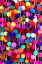 Colorful strands of pom-poms hang at a market Mexico.