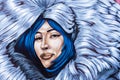 Colorful street art graffiti mural showing face of beautiful eskimo smiley girl among white furs Royalty Free Stock Photo