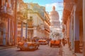 Colorful street in Old Havana with old cars and the Capitol building Royalty Free Stock Photo