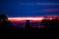 Magnificent dark evening sky with pink and yellow lines of clouds after sunset behind silhouettes of bare trees. Deep horizon. Royalty Free Stock Photo