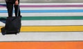 colorful stripes of a pedestrian crossing and traveler with hand trolley in the street in the city