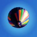 Colorful stripped hot air balloon in flight view from underneath with deep blue sky Royalty Free Stock Photo