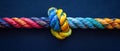 Colorful sturdy rope with knot on blue background. Concept of teamwork, unity, cooperation, partnership, and support. Royalty Free Stock Photo