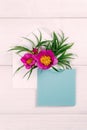 Colorful summer flowers in envelope and turquoise sheet on wooden background.