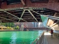Colorful summer view of Chicago River as pedestrians walk on riverwalk under bridge structure