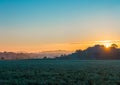 Colorful Sunrise with Misty Field and Hills in Background Royalty Free Stock Photo