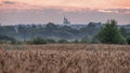 Colorful sunrise in rural with a church among trees on the horizon. Early morning, focus on the background building, hazy look.