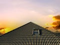 Colorful sunset. Open roof window in velux style with black roof tiles