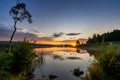 Colorful sunset over a calm lake with reflections in the water and rocks and reeds in the foreground Royalty Free Stock Photo