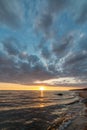 colorful sunset over calm sea beach with dark blue water and dramatic contrasty clouds Royalty Free Stock Photo