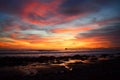 Colorful sunset over the ocean with a pier on the horizon