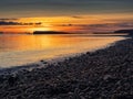 Colorful sunset over ocean, rough stone coast in foreground. Warm and cool color. Salthill beach, Galway city, Ireland. Selective Royalty Free Stock Photo