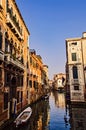 Colorful sunset in a quiet water street in Venice with boats on the canals and beautiful architecture