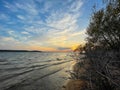 Colorful sunset at Ray Roberts Lake with leafless trees in front of the waves