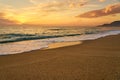 Colorful sunset at the tropical sandy beach, waves with foam hitting sand. Royalty Free Stock Photo