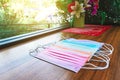 Colorful of surgical masks for Coronavirus Covid-19 protection on wooden table with artificial bouquet in the background.