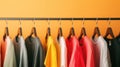Colorful sweatshirts on hangers against an orange background